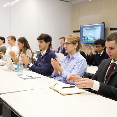 A group of students is applauding in a classroom setting.