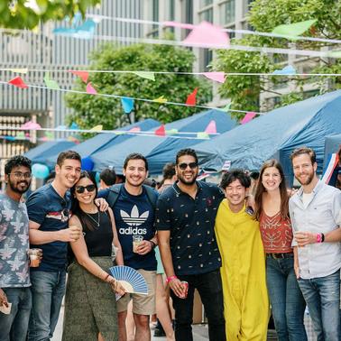 A group of friends posing together at an outdoor event with colorful decorations.