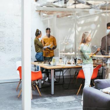 A diverse group of professionals engage in a collaborative meeting inside a modern office space.