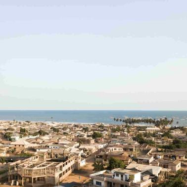Aerial view of a coastal town with numerous buildings and distant views of the ocean.