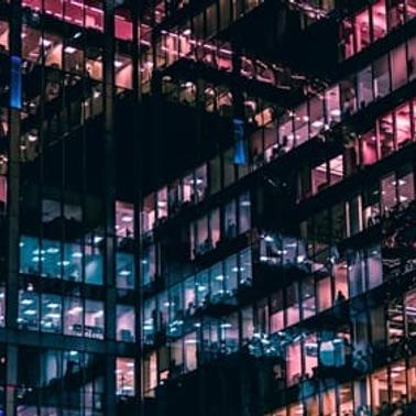 A modern building facade illuminated in vibrant colors at night.