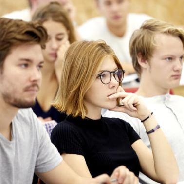A group of students attentively listening in a classroom.