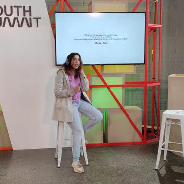A woman is presenting at the South Summit event, standing next to a projected presentation.