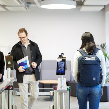 People entering an office through modern electronic access gates.
