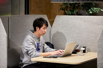 A young man using a laptop at a cafe table