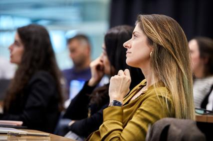 A woman thoughtfully listening in a classroom setting.