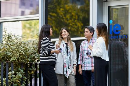 A group of four people engage in a conversation outside a university building.