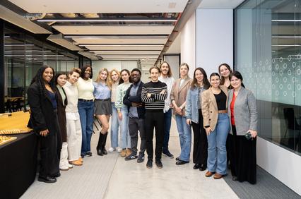 A group of diverse individuals posing together in a modern office space.