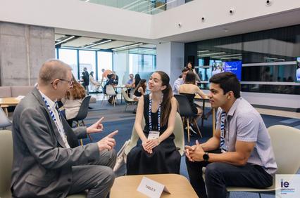 A group of three people engaged in a lively discussion at a conference setting.