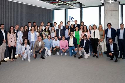 A large group of people posing together in a modern office setting with large windows.