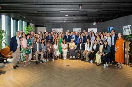 A large group of professionals gathered for a photo in a modern indoor setting.