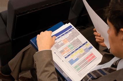 A person sitting and reviewing a colorful spreadsheet or document.