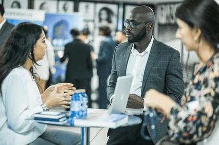 Three professionals engaged in a discussion at a business expo