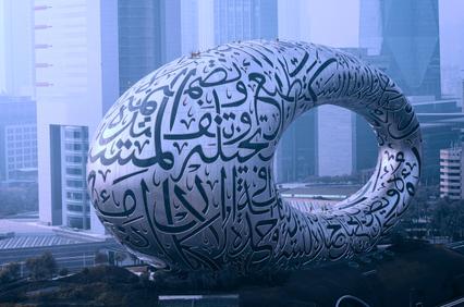 A large, futuristic sculpture featuring intricate calligraphy in an urban setting.