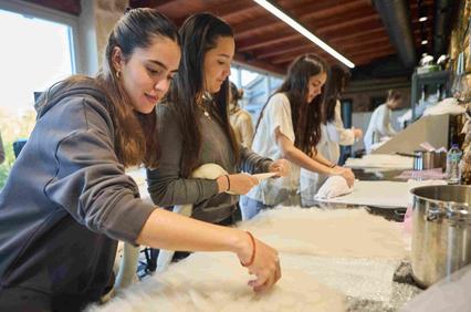 A group of women are engaged in a crafting activity, working with soft materials in a bright workshop.