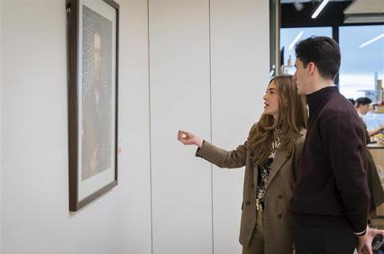 A couple is admiring a painting in an art gallery.
