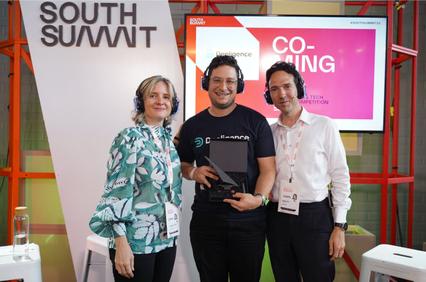 Three people posing together at a tech event, with one of them holding an award.