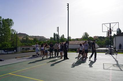 A group of people is gathered on a basketball court during a sunny day.