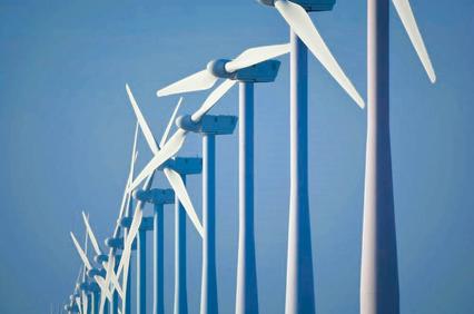A line of wind turbines against a clear blue sky.