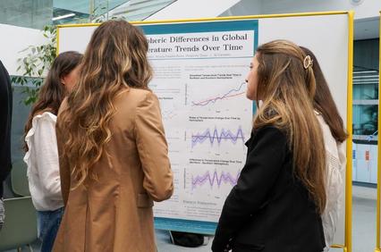 A group of people discussing a poster about global temperature trends.