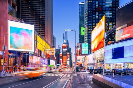 A vibrant urban scene at dusk with colorful billboards and traffic in a busy city.