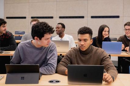 A group of students working on laptops in a classroom setting.