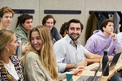 A group of students engaged in a classroom setting, some smiling and interacting.