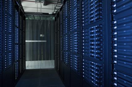 A server room with racks of data servers and a glass door at the end of the aisle.