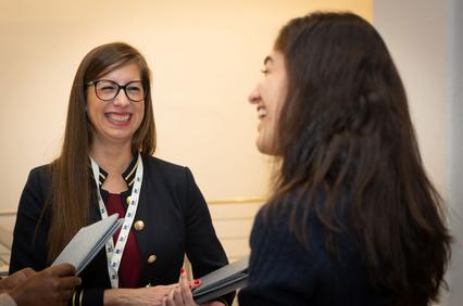 Two women are having a joyful conversation at an event.