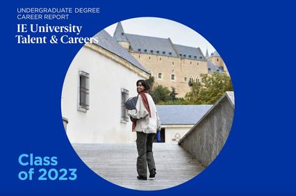 A young woman walks on a campus with historical buildings in the background, featured on a promotional cover for IE University's Career Report for the Class of 2023.