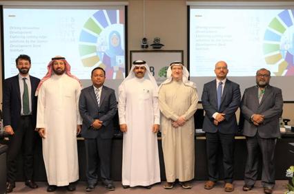 A group of men standing in front of a presentation screen inside a conference room.