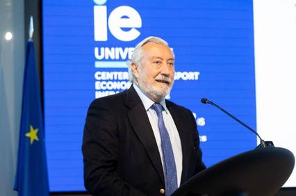 An older man with a beard is giving a speech at a podium with a blue background featuring European Union and IE University logos.