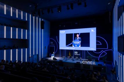 A speaker presents at the CIVICA Global Forum in a modern auditorium.