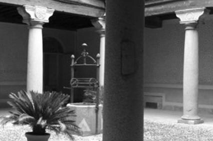 Black and white photo of a serene courtyard with classical columns and a central water well.