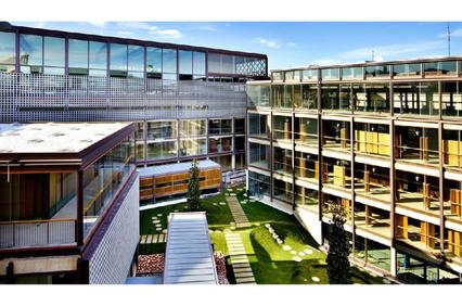 A modern multi-story architectural complex surrounding a landscaped courtyard with green spaces.
