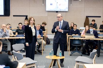 Two professionals are standing in a lecture hall, addressing an audience of students.