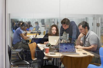 A group of people collaborating in a modern workspace with laptops.