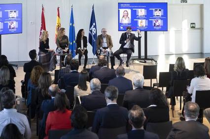 A professional conference with speakers and an audience in a modern room.