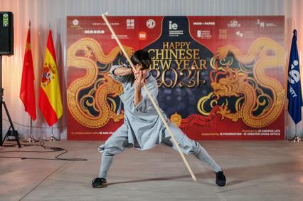 A person performing a martial arts demonstration at a Chinese New Year event, with a banner in the background.