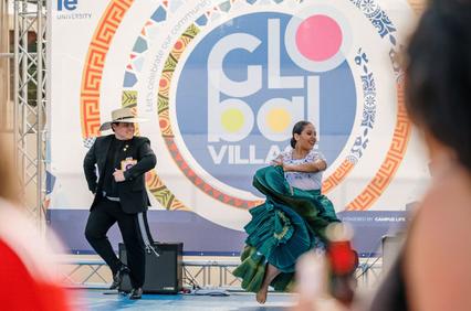 A man and a woman perform a traditional dance on a stage at an event called 'Global Village' at a university.
