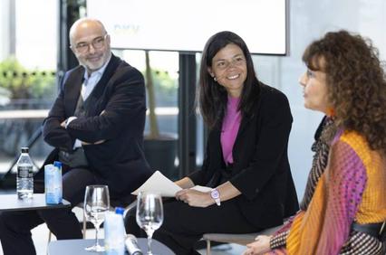 Three professionals, two women and one man, sitting in a modern office setting engaged in a discussion.