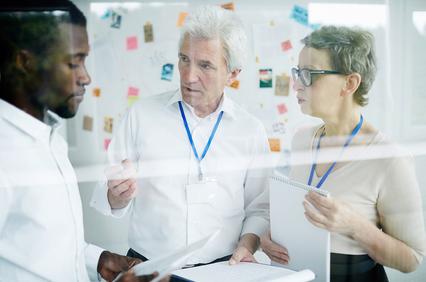 A team of three professionals discussing ideas in an office setting.