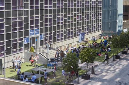 People socializing in a modern urban park with building facades in the background.