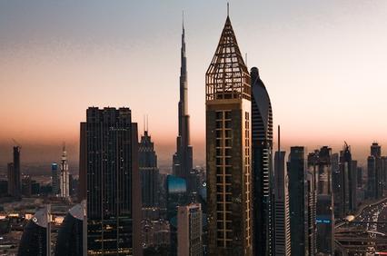 A stunning skyline view of Dubai during sunset, showcasing tall skyscrapers and a clear gradient in the sky.