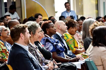 A diverse group of people sitting at a conference, listening attentively.