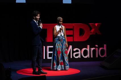 A man and a woman are presenting on stage at a TEDxIE event in Madrid.