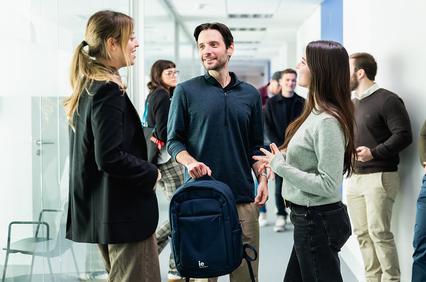A group of three people having a conversation in a modern office setting.