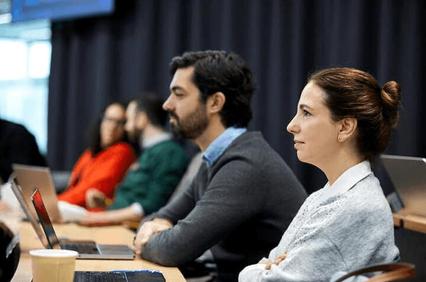 A group of professionals attentively listening during a meeting in a modern office environment.