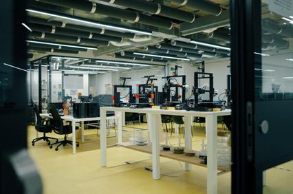 A view of a modern workspace featuring multiple 3D printers and office furniture.