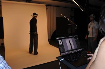 A person is getting their photo taken in a studio setting with a plain background.